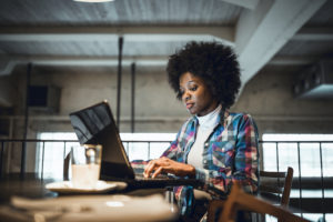 African-American woman working at laptop in cafe.