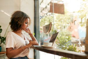 Woman in coffee shop comparing Gusto Payroll and Patriot Payroll